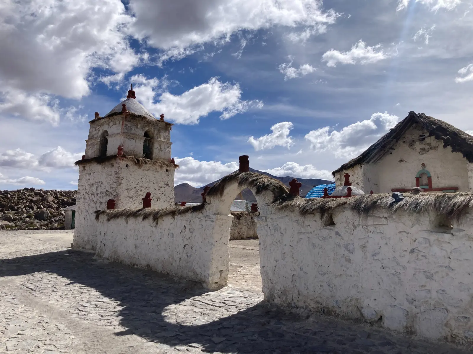 Weiße Kirche von Parinacota mit Strohdächern unter dem Himmel des Altiplano